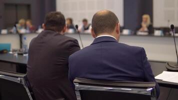 two businessmen discuss business and finance at a round table at a conference. back view video