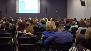 pessoas em a o negócio desenvolvimento fórum. a corredor é completo. Visão a partir de a costas do a corredor com pessoas às uma conferência ou apresentação, mestre aula. Câmera movimento baixa video