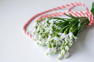 AI generated Snowdrops on white background with red and white rope photo