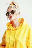 AI generated Fashionable Woman in a Vibrant Yellow Hoodie and Oversized Sunglasses Posing Indoors photo