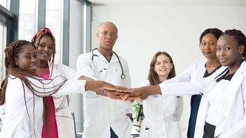 A team of doctors, including women and men of different nationalities, make a gesture of unity video