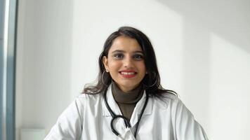 Indian female doctor in a white coat with a stethoscope communicates with the viewer directly into the camera video