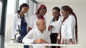 un grupo de cuatro africano americano estudiantes discutir un radiografía con el médico quien hace algunos notas video