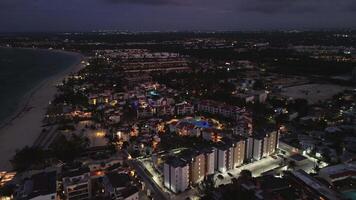 toneel- antenne visie van dar van toeristisch kust- stad tegen een spectaculair Purper zonsondergang lucht, verlichte door levendig stad lichten. vlucht terug video