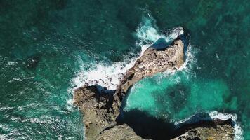 aereo superiore Visualizza di onde rompere su rocce nel un' blu oceano. mare onde su bellissimo spiaggia aereo Visualizza fuco 4k sparo. uccelli occhio Visualizza di oceano onde Crashing contro un vuoto pietra roccia scogliera a partire dal sopra. video