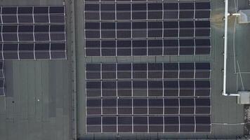 Aerial top down view of modern neighborhood apartment building with solar panels on flat roof providing the residential part with renewable energy from the sun. Ascending video