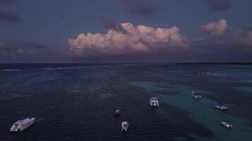 épico dramático pôr do sol sobre a mar a partir de uma drone. aéreo Visão do Sombrio água e ondas. a azul violeta cor do nuvens. macio. Forte vento. barcos e iates. para trás voar video