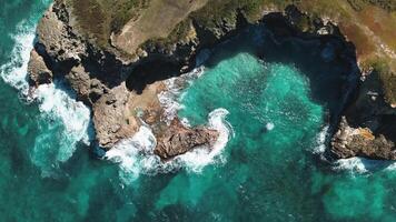 aereo superiore Visualizza di onde rompere su rocce nel un' blu oceano. mare onde su bellissimo spiaggia aereo Visualizza fuco 4k sparo. uccelli occhio Visualizza di oceano onde Crashing contro un vuoto pietra roccia scogliera a partire dal sopra. video