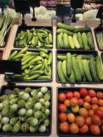 Supermarket shopboard with lug boxes with tomatoes, cucumbers and eggplant. Fresh vegetables for cooking at supermarket in Thailand. photo