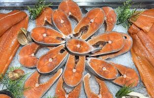 Top view fresh salmon steak, raw red fish fillet on ice in a grocery store on display. Chilled trout on counter in a fish and seafood market. photo