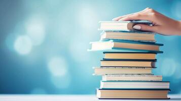 AI generated Delicate hands of a woman gracefully cradle a towering stack of books against a soft, light blue background, each book representing a different facet of education, science, and knowledge photo