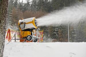 Snow cannon makes artificial snow. Snowmaking systems sprays water to produce snow. photo