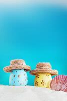 Yellow and blue eggs with polka dot in hat with conch on beach by sea on sunny day. Easter, travel, vacation. Vertical. Copy space photo