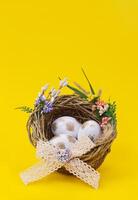 Pascua de Resurrección, cumpleaños póster con blanco dorado huevos en nido con flor en amarillo antecedentes. saludos vertical tarjeta. promoción y compras modelo. Copiar espacio foto