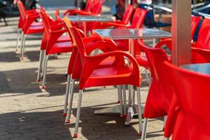 row of red chairs and tables are set up outside photo