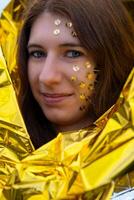 mujer como un fantasía representación con tachuelas en su cara y un dorado rescate cobija foto