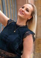 woman in a black lace top is smiling and posing for a photo