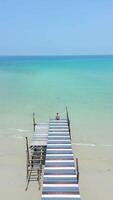 Young woman sitting on a wooden bridge on paradise tropical beach. video