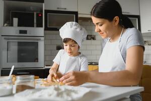 Happy mother and child in kitchen preparing cookies photo