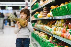 pretty boy with pineapple in supermarket photo