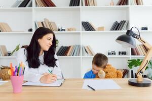 Young female psychologist working with little child in office photo