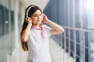 elegante niña escuchando a música rosado auriculares foto