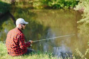 young fisherman fishes near the river. The concept of outdoor activities and fishing photo