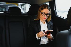 hermosa exitoso mujer de negocios hablar en su móvil teléfono en un asiento trasero de un coche foto