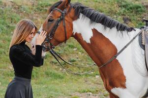 Portrait of young pretty cheerful woman with horse at summer photo