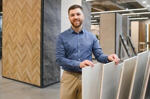 Portrait of a ceramic tile seller. The seller stands against the background of a large assortment of tiles photo