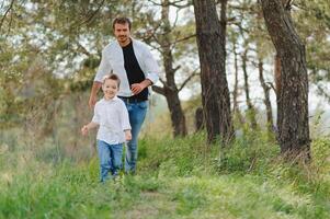 contento padre y hijo sentado en el parque. sonriente joven hombre gasto hora juntos con su hijo. foto