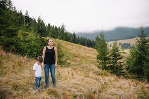 joven mamá con bebé chico de viaje. madre en excursionismo aventuras con niño, familia viaje en montañas. nacional parque. caminata con niños. activo verano vacaciones. foto