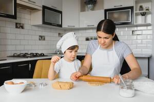 Happy mother and child in kitchen preparing cookies photo