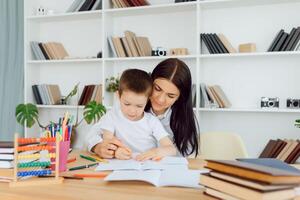 Portrait of handsome boy at workplace with his tutor sitting near by and telling something photo