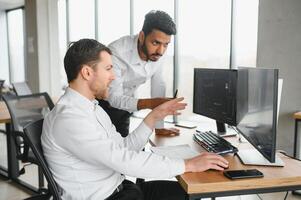 Two men traders sitting at desk at office together looking at data analysis discussing brainstorming successful strategy inspired teamwork concept close-up photo