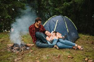 familia cerca el fuego en el bosque. padre con niño en un tienda antecedentes. nacional parque. caminata con niños. activo verano vacaciones. foto