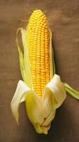 AI generated Single corn cob on brown sackcloth background, viewed from side Vertical Mobile Wallpaper photo