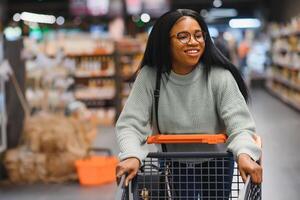African american woman with shopping cart trolley in the supermarket store photo