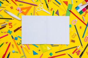 School notebook and stationery over yellow desk. Back to school abstract background. School equipment. Variety of school supplies. Flat lay photo