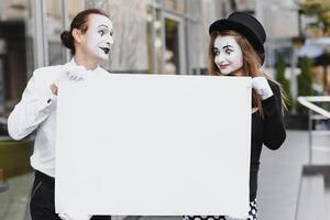 Your text here. Actors mimes holding empty white letter. Colorful portrait with gray background. April fools day photo