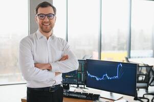 Young bearded man trader at office at table looking camera smiling cheerful photo