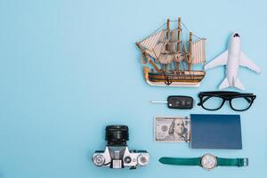 Preparation for Traveling concept, watch, airplane, money, passport, pencils, book, Photo frame, eyeglass on blue background with copy space.