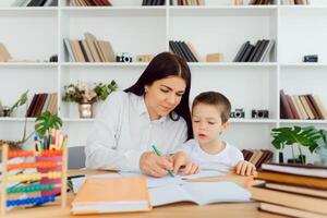 Portrait of handsome boy at workplace with his tutor sitting near by and telling something photo