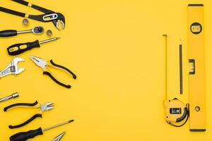 Tools top view on yellow background. Plier, open wrenches, screwdrivers and staple gun flat lay with copy space photo