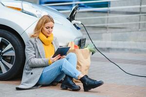 mujer cargando electro coche a el eléctrico gas estación. foto