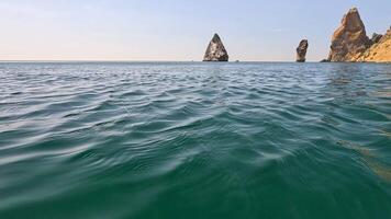 mare acqua superficie. telecamera mosche al di sopra di il calma azzurro mare con vulcanico roccioso sponde su sfondo. nessuno. vacanza ricreazione concetto. astratto nautico estate oceano natura. lento movimento. vicino su video