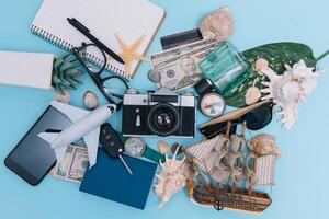 top view travel concept with retro camera films, smartphone, map, passport, compass and Outfit of traveler on blue background with copy space, Tourist essentials, vintage tone effect photo