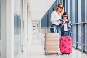 beautiful mother and daughter holding passports and boarding pass at airport photo