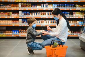 Mother applies sanitizer for cleaning son's hands in public crowded place. Shopping mall photo