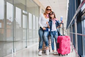 mamá con su hija a el aeropuerto esperando para el avión, mirando eso fuera el ventana. alto temporada y vacaciones concepto. relajarse y estilos de vida foto